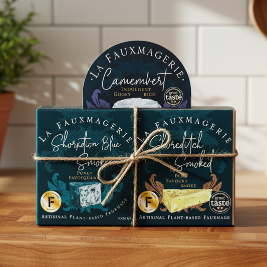 Three packages of 'La Fauxmagerie' cheese on a wooden cutting board with a kitchen background.